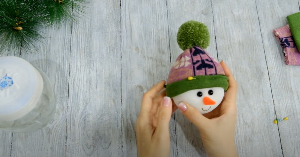 Голова снеговика с шапочкой в руках