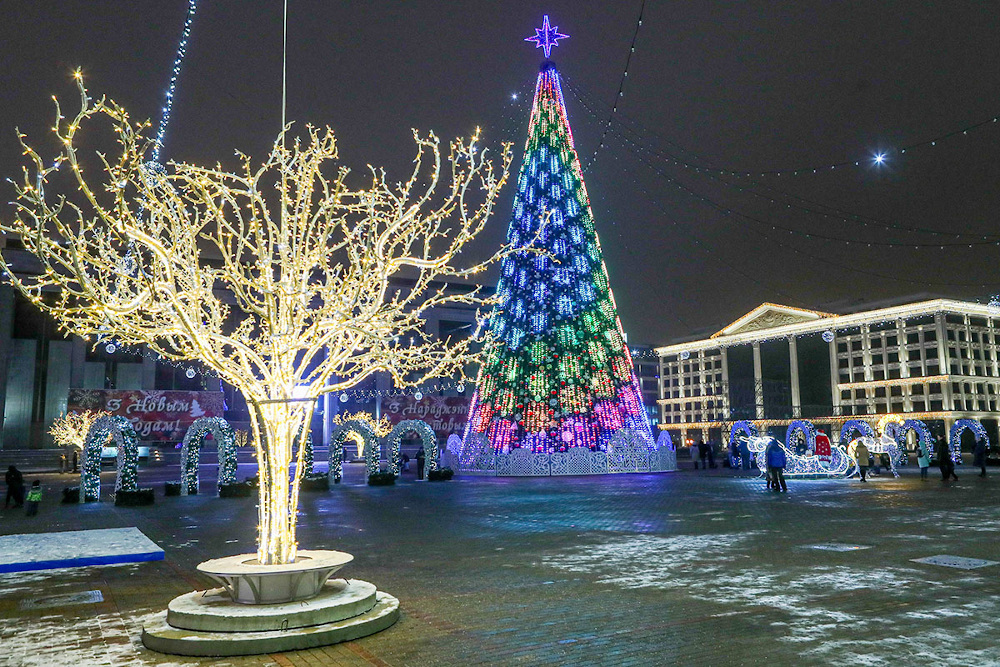 Светящееся дерево на фоне городской наряженной елки