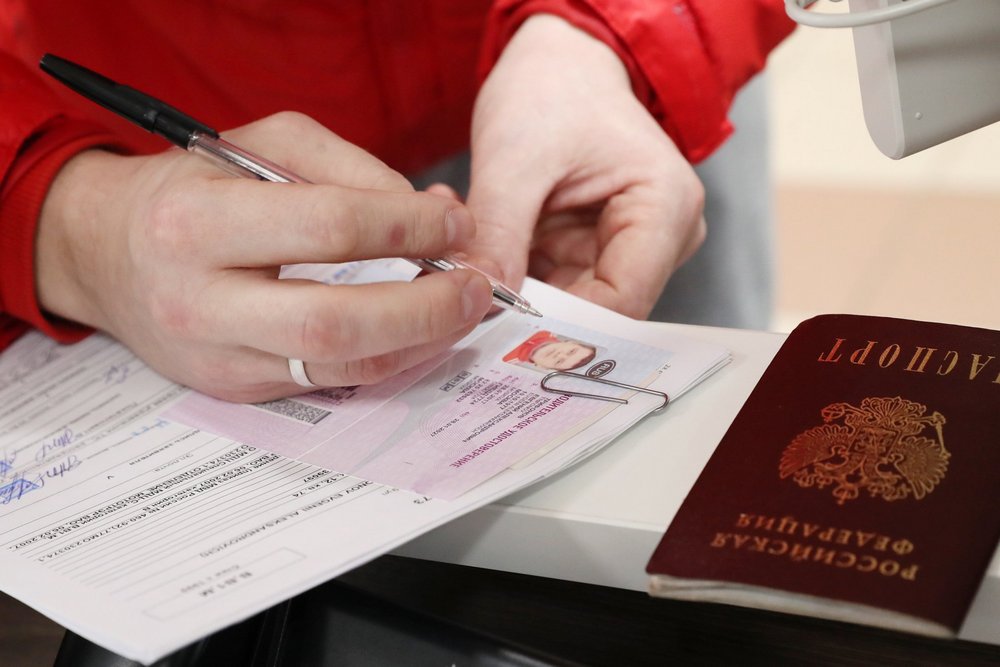 Документы с водительскими правами в руках возле паспорта