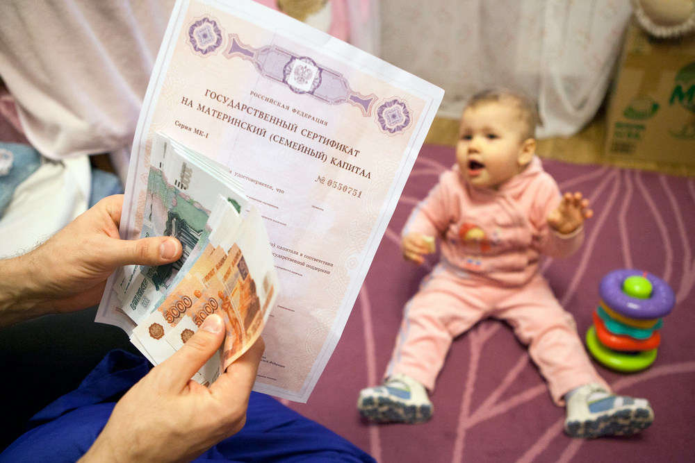 Сертификат и деньги в руках возле ребенка